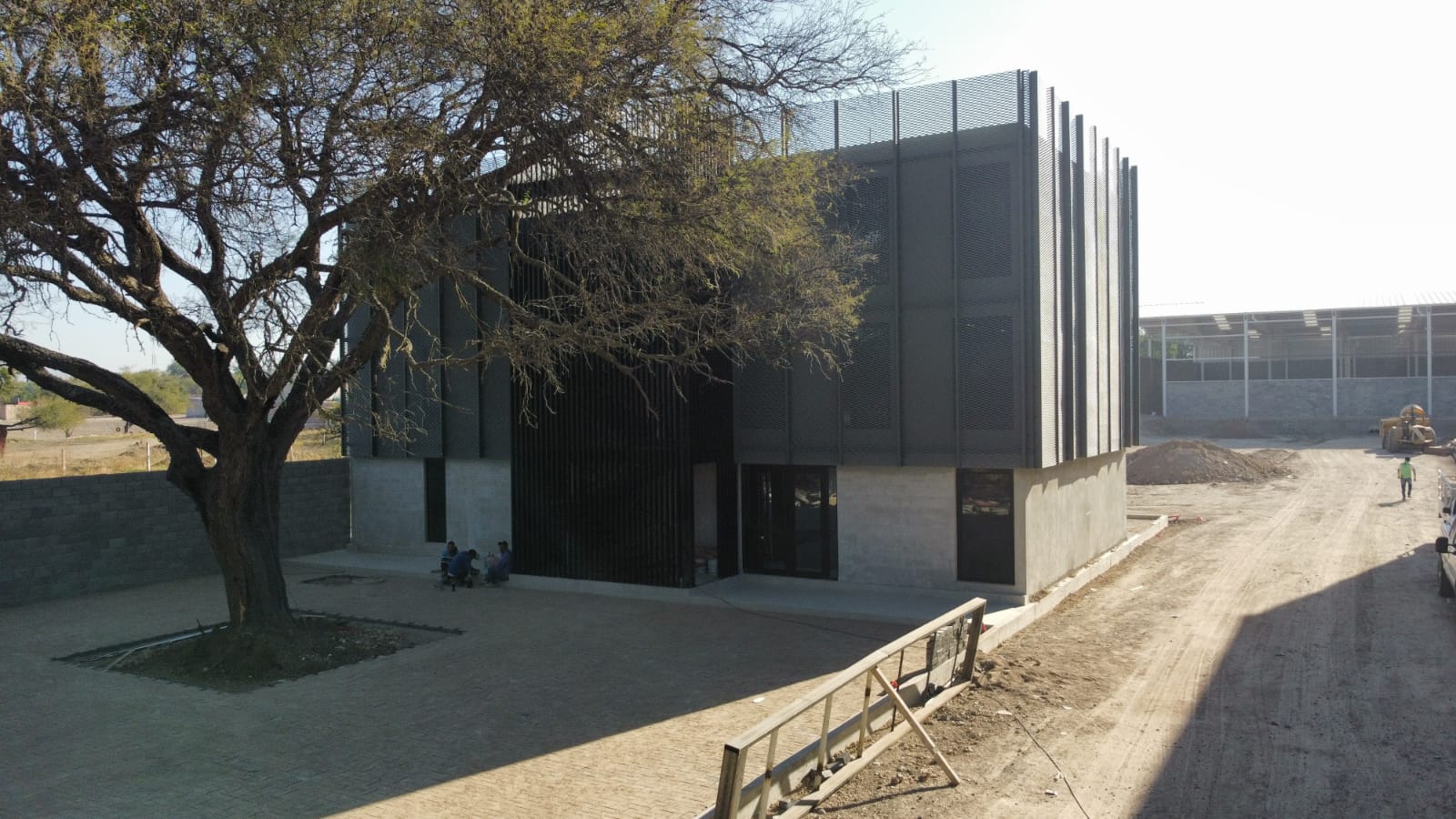 Fachada exterior de nave industrial Trinidad con acceso vehicular y área de maniobras, Fer Et Ciment constructora León