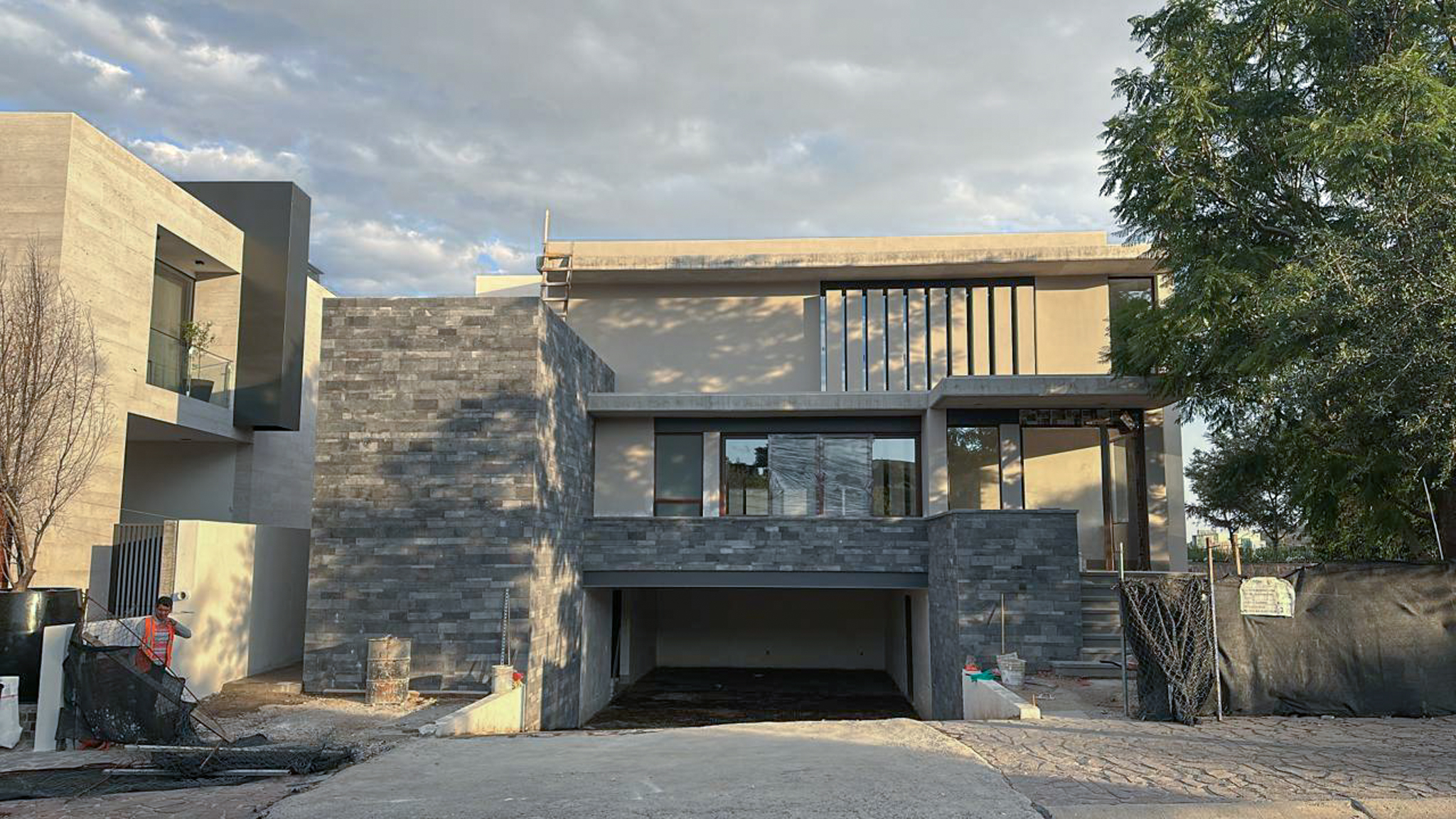 Fachada exterior de casa Misión Cañada con revestimiento de piedra natural y acceso vehicular, construcción residencial Fer Et Ciment León