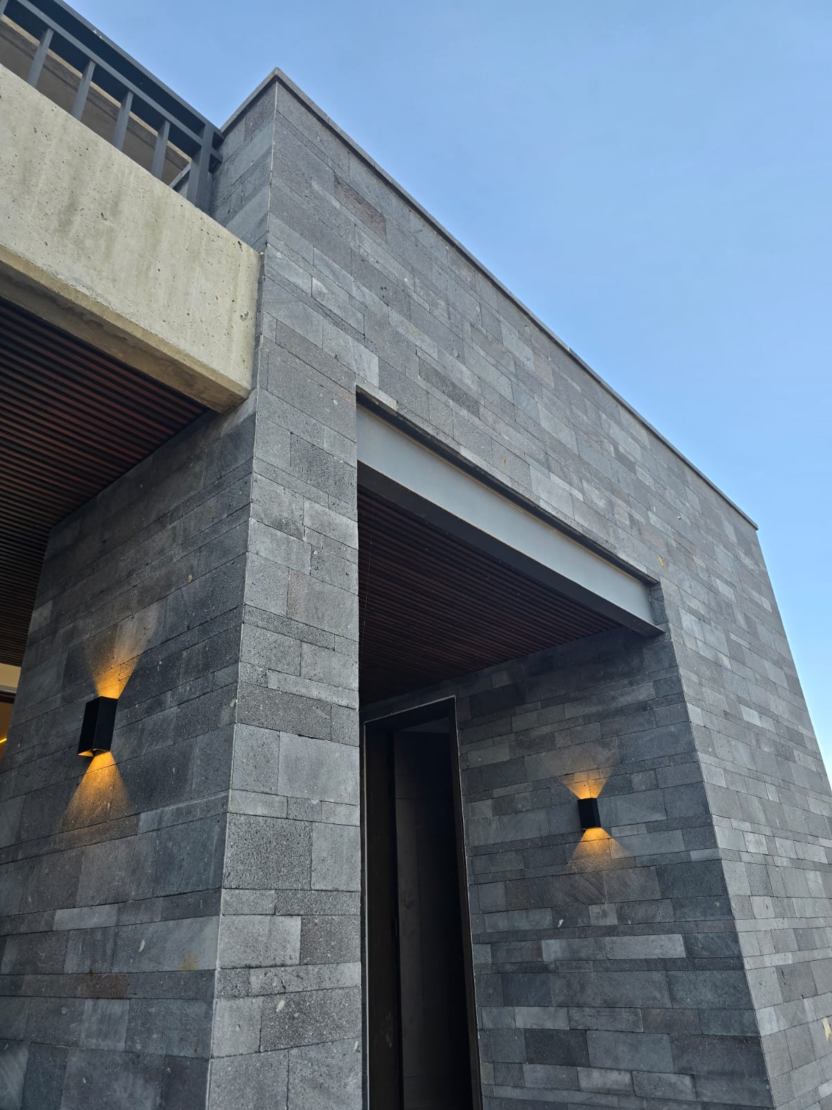 Fachada principal de casa Misión Cañada con acabado en piedra y grandes ventanales, construcción residencial Fer Et Ciment Guanajuato