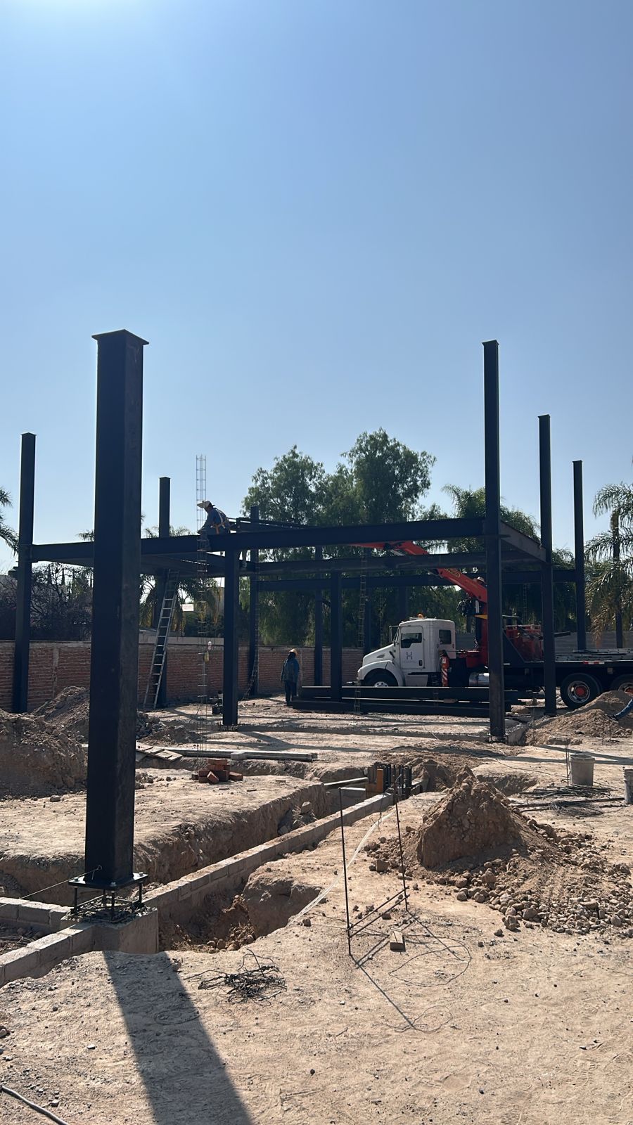 Estructura metálica de Plaza Magnolia en proceso de construcción con palmas decorativas, constructora Fer Et Ciment León